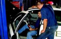 Scott Suter (seated) and James Pounds, both automotive mechanics in Omaha, Neb., use  a Rotunda scanner from Ford Motor Co. to diagnose the reason behind  a “check engine” light on a police squad car. Photo: City of  Omaha
