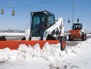 These two skid-steer loaders are working together to clear snow and spread salt on a pedestrian walkway. Photo: Bobcat Co.