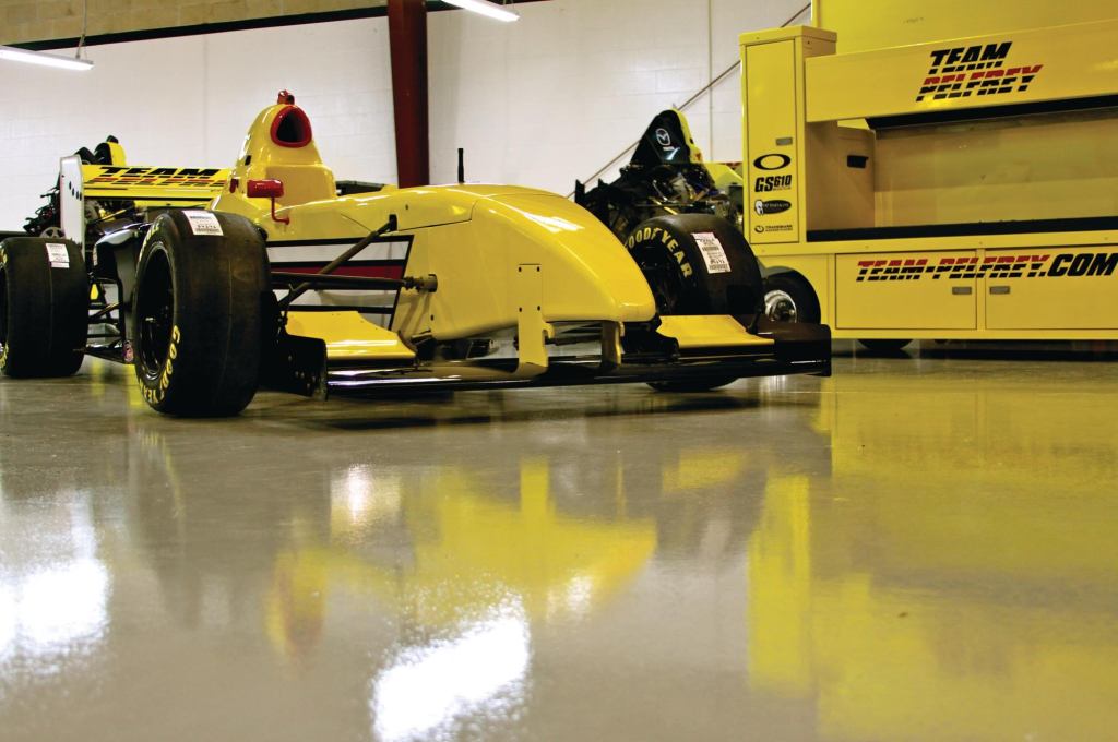 A race car awaits race day on the completed concrete surface.