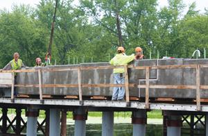 A crew sets a two-piece precast concrete pier cap into position on the State Route 25 Bridge, which bisects the Upper Mississippi National Wildlife and Fish Refuge.