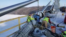 The St. Croix Crossing connects Oak Park Heights, Minnesota, and St. Joseph, Wisconsin. Crews use a hydraulic clamping device (blue) to draw 76 cable strands into a tight circle so dampers can be installed to minimize vibration in the cables due to wind or other loadings.