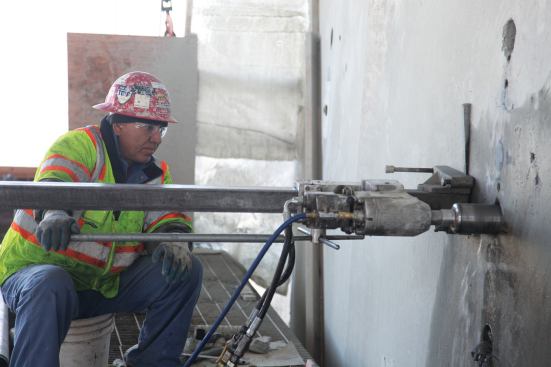 Drilling into the concrete cap beam to prepare for steel saddle installation.