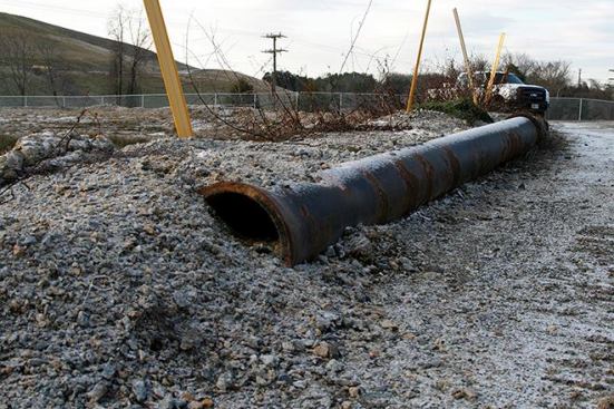 Crews used old steel pipes and large concrete blocks found onsite to secure the perimeter of the dewatering pit. Trucks were able to back up to the edge and dump their loads.