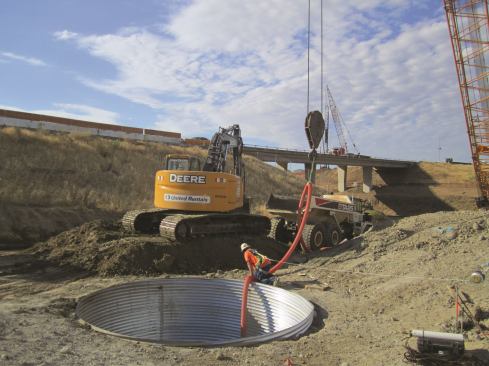 A worker pours concrete into the isolation casing to cast a column.