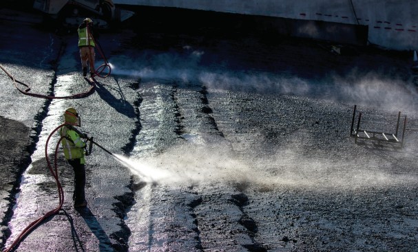 Oct. 25, 2017. Water and compressed air removes loose rocks from the surface of the roller-compacted concrete (RCC) between the upper and lower chute in preparation for a layer of enriched (higher cementitious content) RCC as the temporary wearing surface.