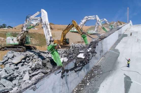 May 8, 2018. With 2018 construction season underway, Ferma Corp. excavators begin removing the temporary RCC sidewalls from the middle chute. Permanent concrete walls will be built in their place later this year. 
