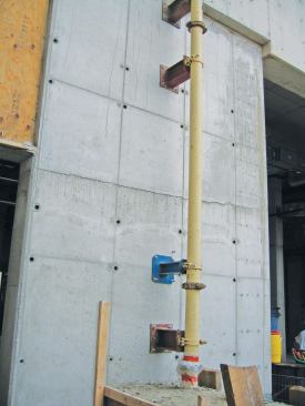 A “Slickline” standpipe is secured to a high rise structure. At the bottom of the photo the pipe is cast into a “thrust block” to secure it