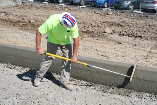 A worker textures the final curb after placement. 