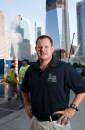 Kurtz stands in front of 1 World Trade Center, the skyscraper being constructed on the site of the former World Trade Center.