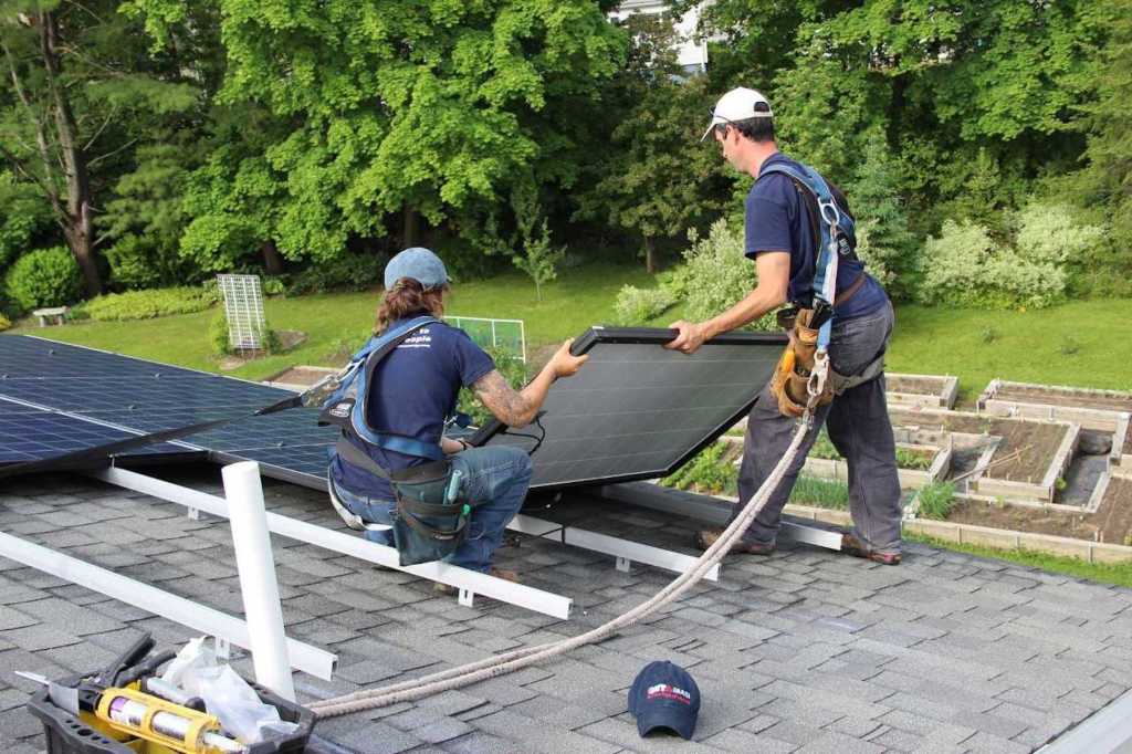 Solar panels are installed on a rooftop in Maine by crew members for Revision Energy.