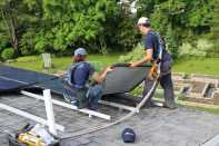 Solar panels are installed on a rooftop in Maine by crew members for Revision Energy.