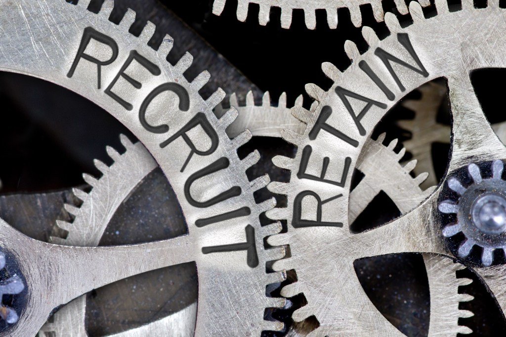 Macro photo of tooth wheel mechanism with imprinted RECRUIT, RETAIN concept words