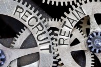 Macro photo of tooth wheel mechanism with imprinted RECRUIT, RETAIN concept words
