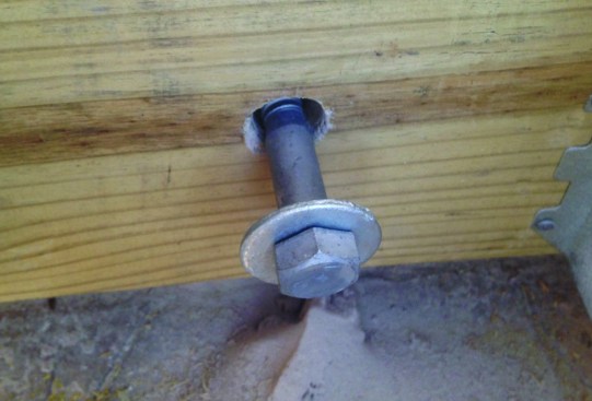 Oversized holes had to be bored through the brick veneer so that the ledger bolts wouldn’t bear on the brick.