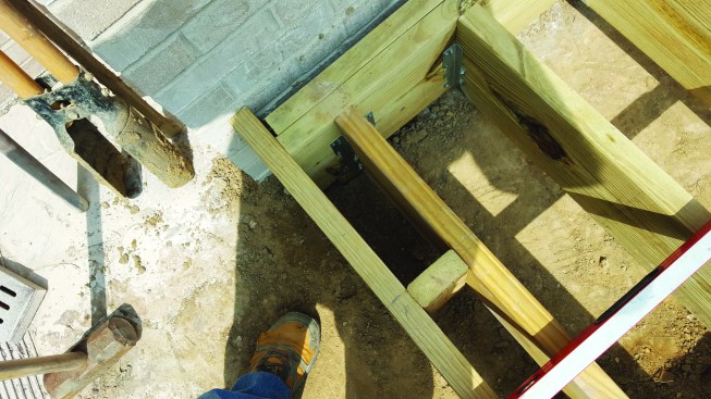 To support the framing at the corner of the deck near the chimney, the author had to install a post, which extends about 9 feet below grade and bears on the chimney footing