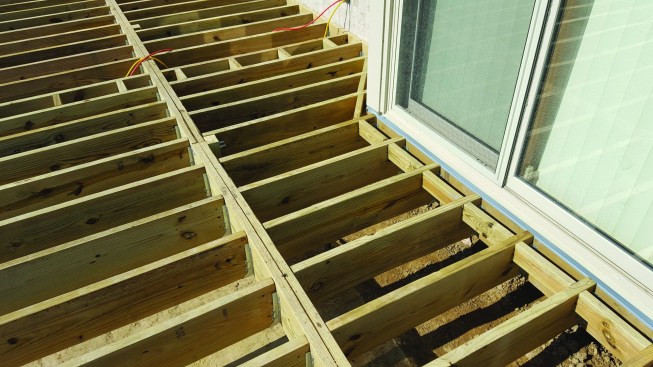 Siding and trim had to be removed from the cantilevered bay before this section of the ledger was installed. Deck loads here are supported primarily by the flush beam, with the cantilever ledger serving mainly for lateral attachment. Note the blocking, which eliminates the need to fasten the decking to the ledger through the L-flashing.