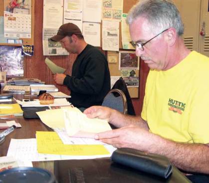 Larry Almaas (foreground) joins other Huttig drivers to review the day's route. They check who is to be served, what's to be delivered, and what order those deliveries will occur. Drivers may change the order if they know a customer further down the list has a special need.