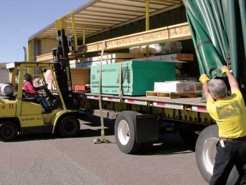 After making a tight left turn into the yard, Almaas has to pull his trailer's heavy curtain all the way open in order for a forklift driver at Marson & Marson Lumber in Wenatchee, Wash., to take off a shipment of I-joists.