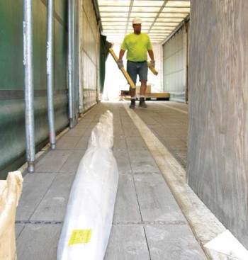 Nearing the end of his deliveries–with just some vinyl trim left to hand-carry into a store–Crossland picks up blocks of wood used to support previously delivered pallets and stores them in a box so they won't rattle around the truck. Wolf drivers are required to deliver their trailers back to the yard clean and organized.
